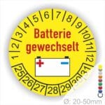 Prüfaufkleber, Prüfplakette rund, Farbe- Gelb, Text "Batterie gewechselt" in Rot. Icon Batterie, Startjahr- 25, Monatszahlen Oben und Jahreszahlen Unten in Kreisform.