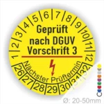 Gelbes Prüfzeichen mit der Aufschrift "Geprüft nach DGUV Vorschrift 3", das den nächsten Prüftermin anzeigt. Durchmesser zwischen 20 und 50 mm.