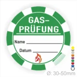 Grünes Aufkleber-Design für Gasprüfungen mit Platz für Name und Datum, Durchmesser 30-50 mm, enthält ein feuerförmiges Symbol. Ideal für Sicherheitskennzeichnungen in der Gasinstallation.