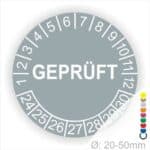 Prüfplakette rund, Farbe- Grau, Text "GEPRÜFT" in Weiß. Startjahr- 24, Monatszahlen Oben und Jahreszahlen Unten in Kreisform.