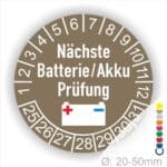 Prüfplaketten, Wartungsaufkleber rund, Farbe- Braun, Text "Nächste Batterie/Akku Prüfung" in Weiss. Icon Batterie, Startjahr- 25, Monatszahlen Oben und Jahreszahlen Unten in Kreisform.
