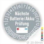 Wartungssiegel, Mehrjahresplakette rund, Farbe- Grau, Text "Nächste Batterie/Akku Prüfung" in Weiss. Icon Batterie, Startjahr- 25, Monatszahlen Oben und Jahreszahlen Unten in Kreisform.