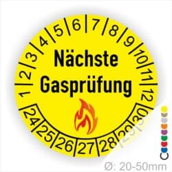 Prüfplaketten rund, Farbe- Gelb, Text "Nächste Gasprüfung" in Schwarz danach eine Flamme als Pictogramm oder Icon in Rot, Startjahr- 24, Monatszahlen Oben und Jahreszahlen Unten in Kreisform. Über den Jahreszahlen.