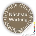 Prüfplaketten, Prüfetiketten rund, Farbe- Braun, Text "Nächste Wartung" in Weiß. Startjahr- 26, Monatszahlen Oben und Jahreszahlen Unten in Kreisform.