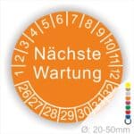 Prüfplaketten, Prüfetiketten rund, Farbe- Orange, Text "Nächste Wartung" in Weiß. Startjahr- 26, Monatszahlen Oben und Jahreszahlen Unten in Kreisform.