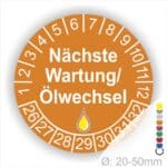 Prüfetiketten, Prüfaukleber rund, Farbe- Orange, Text "Nächste Wartung/Ölwechsel" in Weiß. Startjahr- 26, Monatszahlen Oben und Jahreszahlen Unten in Kreisform, über den Jahreszahlen ein Öltropfen als Icon/Piktogramm in Gelb.
