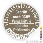 Prüfplakette mit Text Geprüft nach Dguv Vorschrift 4 und Nächster Prüftermin mit zwischen Strich in Weiss. Plaketten Farbe- Braun und Text in Weiss. Monatszahlen oben und Jahreszahlen unten beginnend mit Startjahr- 26