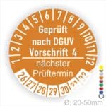 Prüfplakette mit Text Geprüft nach Dguv Vorschrift 4 und Nächster Prüftermin mit zwischen Strich in Weiss. Plaketten Farbe- Orange und Text in Weiss. Monatszahlen oben und Jahreszahlen unten beginnend mit Startjahr- 26