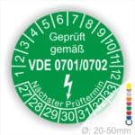 Grünes Prüfzeichen mit der Aufschrift „Geprüft gemäß VDE 0701/0702“, das den nächsten Prüftermin anzeigt. Das Symbol weist auf die Sicherheit von elektrischen Geräten hin und ist für Geräte mit einem Durchmesser von 20-50 mm geeignet.