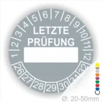 Grauer Prüfaufkleber mit der Aufschrift "LETZTE PRÜFUNG" und Platz für das Datum. Der Aufkleber zeigt Zahlen von 1 bis 12 und von 26 bis 32. Durchmesser von 20-50 mm, geeignet für regelmäßige Sicherheitsüberprüfungen.