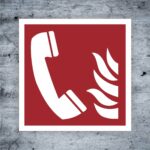 Symbol für Notruf mit Telefon und Flamme auf rotem Hintergrund, geeignet für Sicherheits- und Brandschutzinformationen.