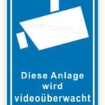 Schild zur Videoüberwachung mit der Aufschrift „Diese Anlage wird videoüberwacht“ auf blauem Hintergrund, das auf Sicherheitsmaßnahmen hinweist.
