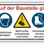 Sicherheitszeichen auf Baustelle mit Anweisungen: Kopfschutz benutzen, nicht unter schwebende Last treten, Sicherheitsschuhe tragen.