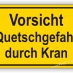 Warnschild mit der Aufschrift "Vorsicht Quetschgefahr durch Kran" in gelber Farbe, das auf potenzielle Gefahren durch Krane hinweist.