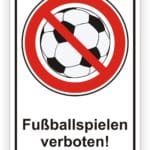 Schild mit der Aufschrift "Fußballspielen verboten!" und einem durchgestrichenen Fußball, das auf ein Verbot von Fußballspielen hinweist.