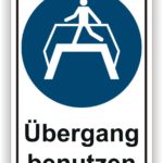 Hinweisschild für Fußgänger mit der Aufforderung, den Übergang zu benutzen, dargestellt durch ein Piktogramm einer Person auf einem Zebrastreifen.