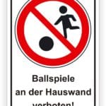 Symbolisches Verbotsschild für Ballspiele an der Hauswand mit einem Piktogramm eines spielenden Kindes und dem Hinweis, dass solche Aktivitäten verboten sind.