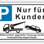 Parkplatzschild mit der Aufschrift "Nur für Kunden" und einer Illustration eines Abschleppwagens, der ein falsch geparktes Auto abschleppt. Hinweis auf kostenpflichtiges Abschleppen von unbefugten Fahrzeugen.