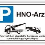 Parkplatzschild für HNO-Arztpraxis mit Hinweis auf Abschleppdienst für falsch parkende Fahrzeuge.