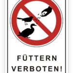 Schild mit dem Hinweis "Füttern verboten!" und Symbolen von Vögeln, das auf die Regelung des Fütterns von Wildtieren hinweist.