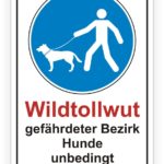 Hinweisschild über Wildtollwut in einem gefährdeten Bezirk, das Hundehalter auffordert, ihre Hunde unbedingt an der Leine zu führen.