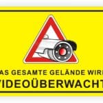 Warnschild für Videoüberwachung auf gelbem Hintergrund mit einer Kamera, die anzeigt, dass das gesamte Gelände überwacht wird.