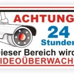 Schild mit der Aufschrift „Achtung! 24 Stunden Dieser Bereich wird videoüberwacht“ und einer Abbildung einer Überwachungskamera, die auf Sicherheit und Überwachung hinweist.