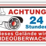Schild mit der Aufschrift "Achtung 24 Stunden Videoüberwachung" und einer Grafik einer Überwachungskamera, die auf die Sicherheitsmaßnahmen des Geländes hinweist.