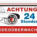Achtungsschild mit Kamera-Illustration, das auf 24-Stunden-Videobeobachtung hinweist.