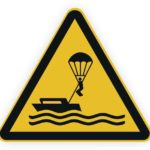 Warnschild für Wassersport: Person mit Fallschirm wird von einem Boot gezogen.