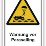 Warnschild für Parasailing mit einem Boot und einem Gleitschirmfahrer über Wasser.
