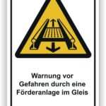 Warnschild zur Sicherheit, das vor Gefahren durch eine Förderanlage im Gleis warnt, mit gelbem Dreieck und Symbol für Förderband.