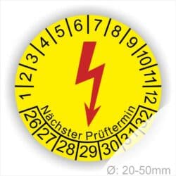 E-Check Prüfplaketten rund, Farbe- Gelb, ein Elektro- Pfeil in Rot, Startjahr- 26, Monatszahlen Oben und Jahreszahlen Unten in Kreisform. Über den Jahreszahlen Text "Nächster Prüftermin"