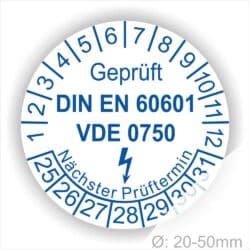 Prüfsiegel, Prüfplaketten rund, Farbe- Weiß, Text "Geprüft DIN EN 60601 und VDE 0750" in Blau danach ein Elektro- Pfeil in Blau, Startjahr- 25, Monatszahlen Oben und Jahreszahlen Unten in Kreisform. Über den Jahreszahlen Text "Nächster Prüftermin"