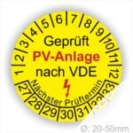 Prüfplaketten rund, Farbe- Gelb, Text "Geprüft PV-Anlage nach VDE" in Schwarz danach ein Elektro- Pfeil in Rot, Startjahr- 27, Monatszahlen Oben und Jahreszahlen Unten in Kreisform. Über den Jahreszahlen Text "Nächster Prüftermin"