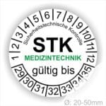 Prüfetiketten rund, Farbe- Weiß, Text "Sicherheitstechnische Kontrolle, STK MEDIZINTECHNIK gültig bis" in Schwarz. Startjahr- 29, Monatszahlen Oben und Jahreszahlen Unten in Kreisform. über den Jahreszahlen Text.