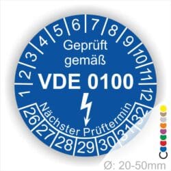 Prüfplaketten rund Farbe- Blau, Text "Geprüft gemäß VDE 0100" in Weiß danach ein Elektro- Pfeil in Weiß, Startjahr- 26, Monatszahlen Oben und Jahreszahlen Unten in Kreisform. Über den Jahreszahlen Text "Nächster Prüftermin"