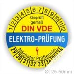 Prüfplaketten rund, Farbe- Gelb in der Mitte ein Streifen in Blau, Text oberer Teil "Geprüft gemäß DIN-VDE" in Schwarz. Mittig Streifen in Blau mit dem Text " ELEKTRO-PRÜFUNG", Danach Elektropfeil in Rot Startjahr- 29, Monatszahlen Oben und Jahreszahlen Unten in Kreisform. Über den Jahreszahlen Text "Nächster Prüftermin"