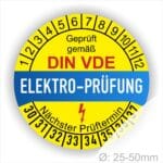 Prüfplaketten rund, Farbe- Gelb in der Mitte ein Streifen in Blau, Text oberer Teil "Geprüft gemäß DIN-VDE" in Schwarz. Mittig Streifen in Blau mit dem Text " ELEKTRO-PRÜFUNG", Danach Elektropfeil in Rot Startjahr- 30, Monatszahlen Oben und Jahreszahlen Unten in Kreisform. Über den Jahreszahlen Text "Nächster Prüftermin"