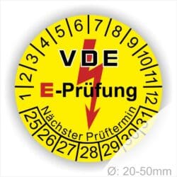 Prüfplaketten rund, Farbe- Gelb, Text "VDE E-Prüfung" in Schwarz in Hinergrund ein Elektro- Pfeil in Rot, Startjahr- 25, Monatszahlen Oben und Jahreszahlen Unten in Kreisform. Über den Jahreszahlen Text "Nächster Prüftermin"