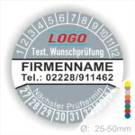 Graue Prüfplakette mit Monats- und Jahresring zur Kennzeichnung des nächsten Prüftermins, personalisierbar mit Firmenname, Logo, Telefonnummer und Wunschtext. Selbstklebender Prüfaufkleber für Wartung, Sicherheitsprüfung und Betriebsmittelkennzeichnung.