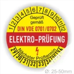 Runde Elektroprüfungs-Plakette mit dem Aufdruck "Geprüft gemäß DIN VDE 0701/0702" und dem Hinweis auf den nächsten Prüftermin. Die Plakette ist gelb mit roten und schwarzen Schriftzügen und hat einen Durchmesser von 25-50 mm.