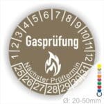 Prüfplaketten, Prüfetiketten rund, Farbe- Braun, Text "Gasprüfung" in Weiß danach eine Flamme als Pictogramm oder Icon in Weiß, Startjahr- 25, Monatszahlen Oben und Jahreszahlen Unten in Kreisform. Über den Jahreszahlen Text "Nächster Prüftermin"