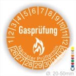 Prüfplaketten, Prüfetiketten rund, Farbe- Orange, Text "Gasprüfung" in Weiß danach eine Flamme als Pictogramm oder Icon in Weiß, Startjahr- 26, Monatszahlen Oben und Jahreszahlen Unten in Kreisform. Über den Jahreszahlen Text "Nächster Prüftermin"