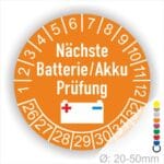 Prüfetiketten, Prüfplakette rund, Farbe- Orange, Text "Nächste Batterie/Akku Prüfung" in Weiß. Icon Batterie, Startjahr- 25, Monatszahlen Oben und Jahreszahlen Unten in Kreisform.