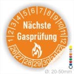 Prüfetiketten, Prüfplaketten rund, Farbe- Orange, Text "Nächste Gasprüfung" in Weiß danach eine Flamme als Pictogramm oder Icon in Weiß, Startjahr- 26, Monatszahlen Oben und Jahreszahlen Unten in Kreisform.