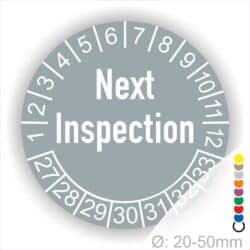 Prüfetiketten, Prüfaukleber rund, Farbe- Grau, Text auf Englisch "Next Inspection" in Weiß. Startjahr- 27, Monatszahlen Oben und Jahreszahlen Unten in Kreisform.