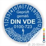 Prüfetiketten rund, Farbe- Blau, Text "Geprüft gemäß VDE 0100-0723" in Weiß danach ein Elektro- Pfeil in Weiß, Startjahr- 26, Monatszahlen Oben und Jahreszahlen Unten in Kreisform. Über den Jahreszahlen Text "Nächster Prüftermin"