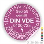 Prüfaufkleber rund, Farbe- Lila, Text "Geprüft gemäß VDE 0100-0723" in Weiß danach ein Elektro- Pfeil in Weiß, Startjahr- 27, Monatszahlen Oben und Jahreszahlen Unten in Kreisform. Über den Jahreszahlen Text "Nächster Prüftermin"