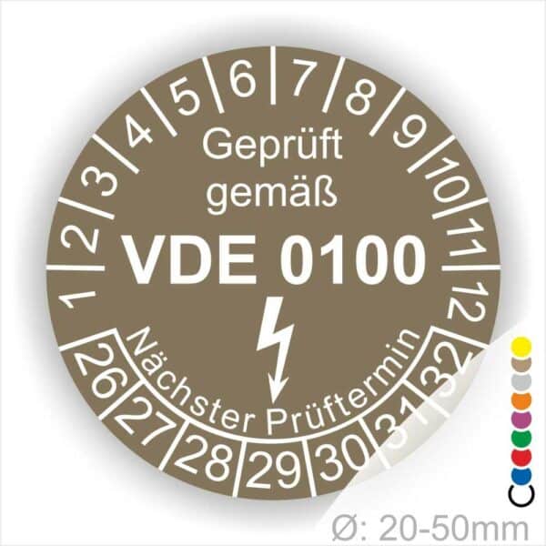Prüfplaketten rund Farbe- Braun, Text "Geprüft gemäß VDE 0100" in Weiß danach ein Elektro- Pfeil in Weiß, Startjahr- 26, Monatszahlen Oben und Jahreszahlen Unten in Kreisform. Über den Jahreszahlen Text "Nächster Prüftermin"
